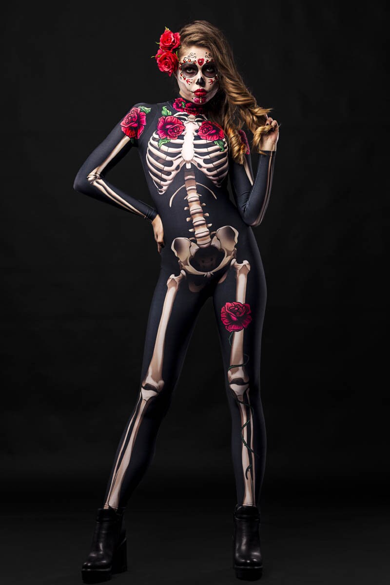 Women wearing a skeleton bodysuit with red rose accents and matching floral cloak, styled for Halloween. The outfit is inspired by Day of the Dead with intricate sugar skull face makeup and a crown of red roses.