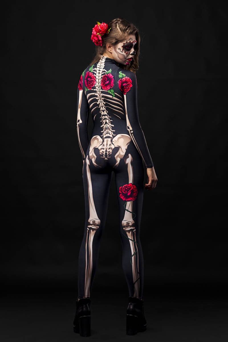 Women in skeleton bodysuit with red roses and floral cloak, Day of the Dead-inspired, with sugar skull makeup and red rose crown.