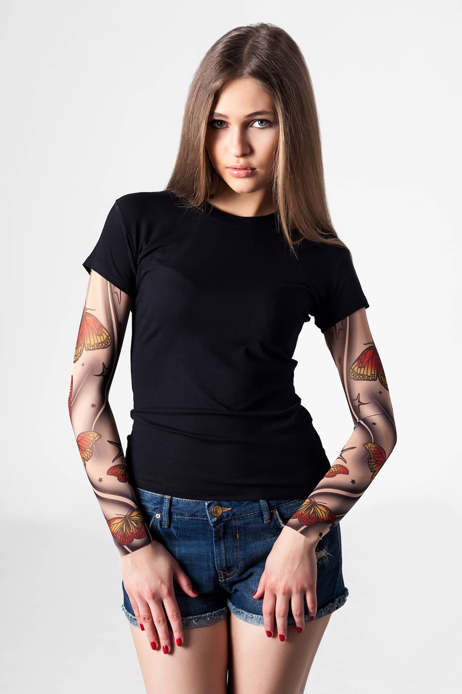 Damski t-shirt z tatuażem Blue Butterflies – delikatny motyw żółto-pomarańczowych motyli, widok z przodu z rękami na udach