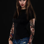 Woman posing in the Zombie Halloween T-shirt with tattoo mesh sleeves, showcasing the detailed zombie designs on the sleeves, great for Halloween or as a fun, casual top.