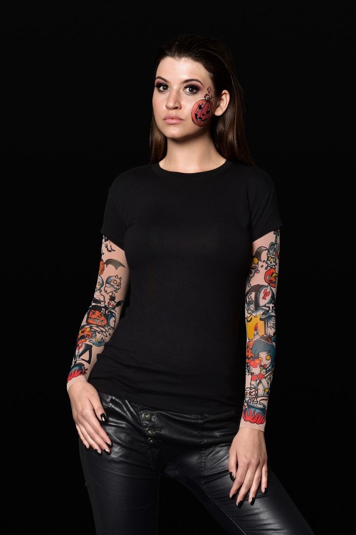 Woman posing in the Pumpkin Halloween T-shirt with tattoo pumpkin sleeves, showcasing the Halloween-themed design, great for Halloween parties or as a statement top.