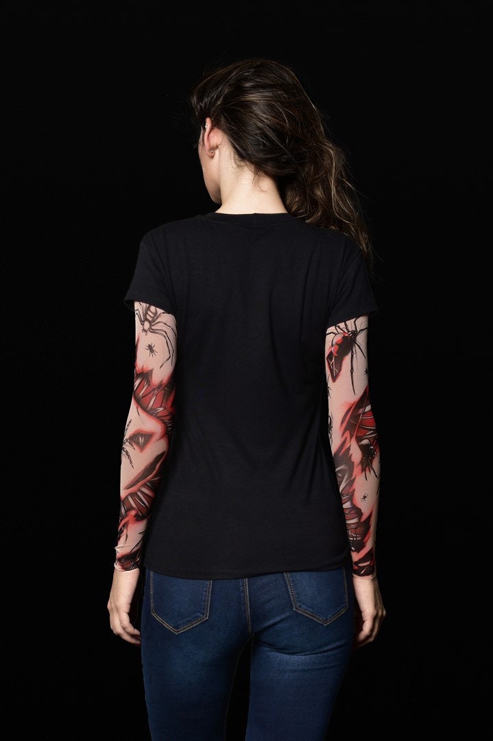 Woman posing in the Spiders Halloween T-shirt with tattoo spiderweb sleeves, showcasing the spooky sleeve design, perfect for Halloween or as a unique statement top.