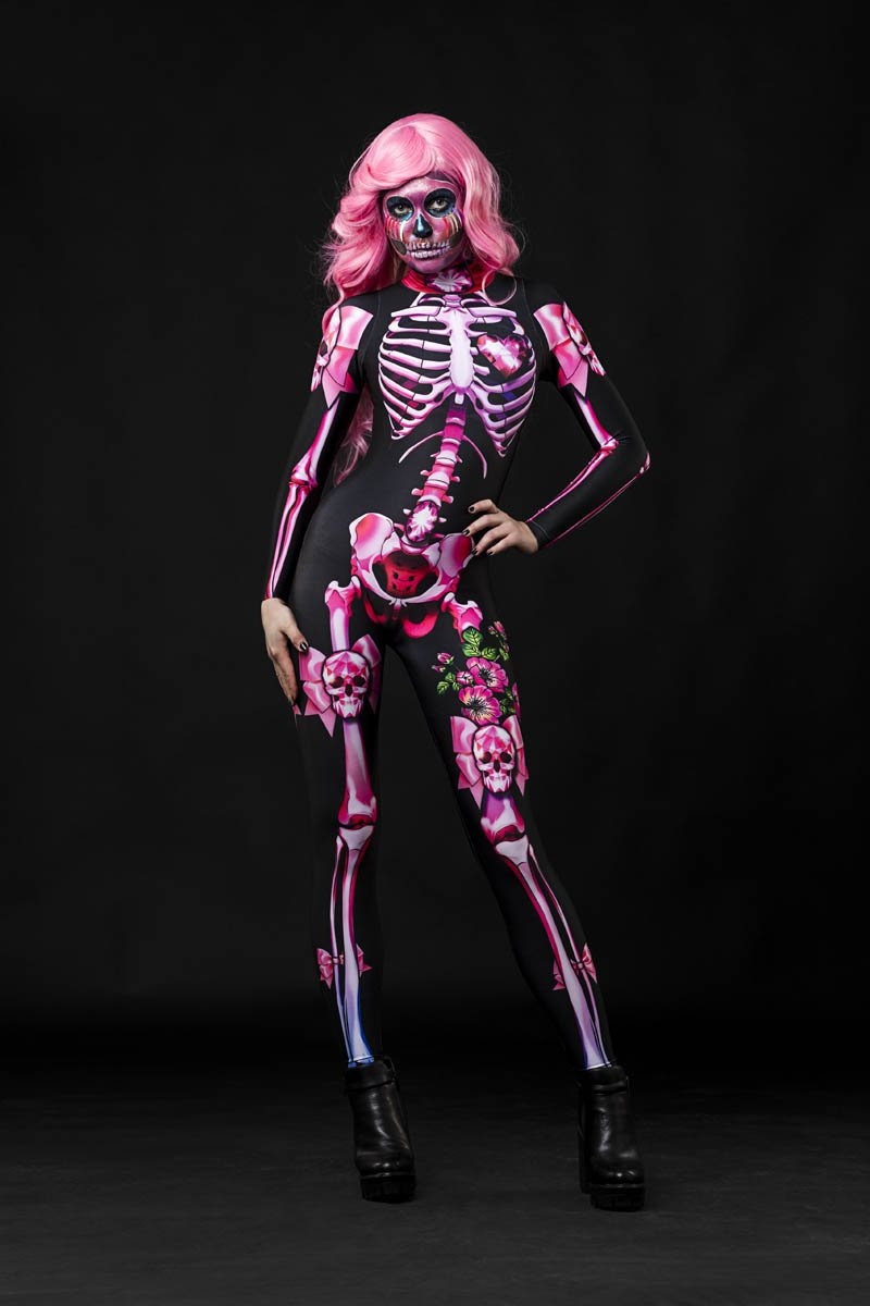 Woman wearing the Pink Sugar Skull Skeleton costume, a pastel pink full-body catsuit with sugar skull accents, ideal for Halloween parties or Day of the Dead events.