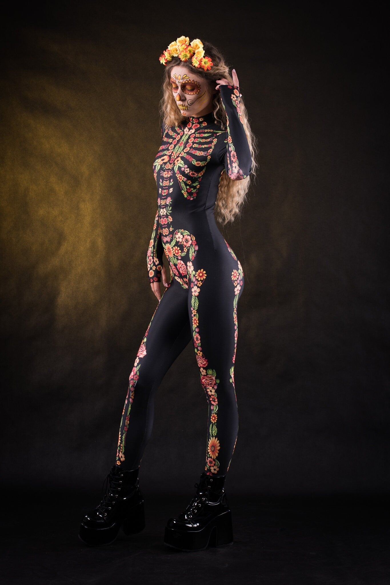 Woman wearing the Flower Skeleton costume, full-body skeleton catsuit with bold orange, yellow, and green floral accents, perfect for Halloween or Day of the Dead festivities.