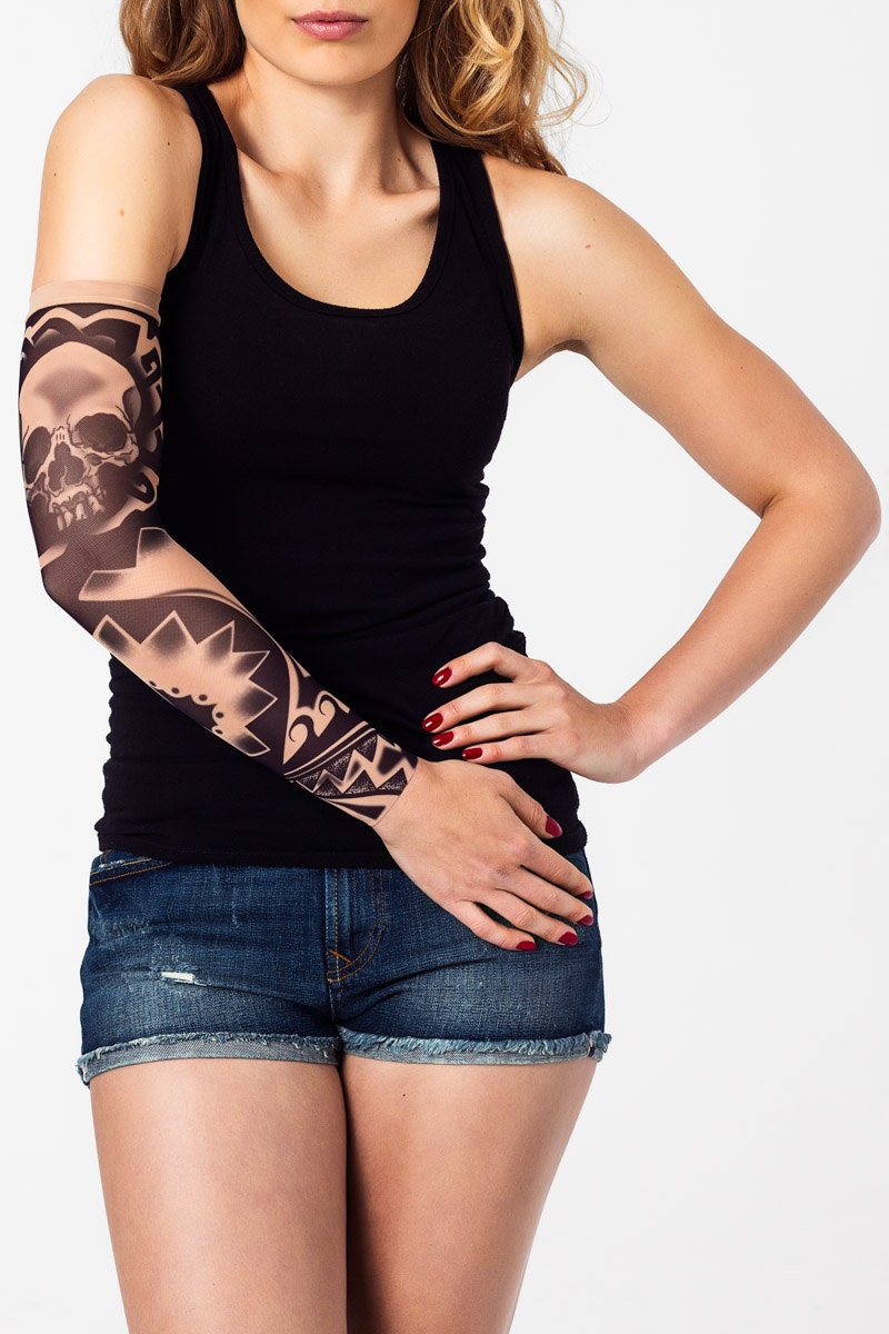 Rękaw z tatuażem czarnej czaszki i motywów tribalowych – na damskiej ręce, widok z przodu