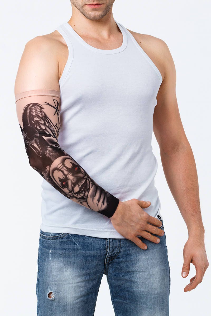 Rękaw z tatuażem clowna z diabelskimi oczami i czarnym krukiem – na męskiej ręce, widok z przodu