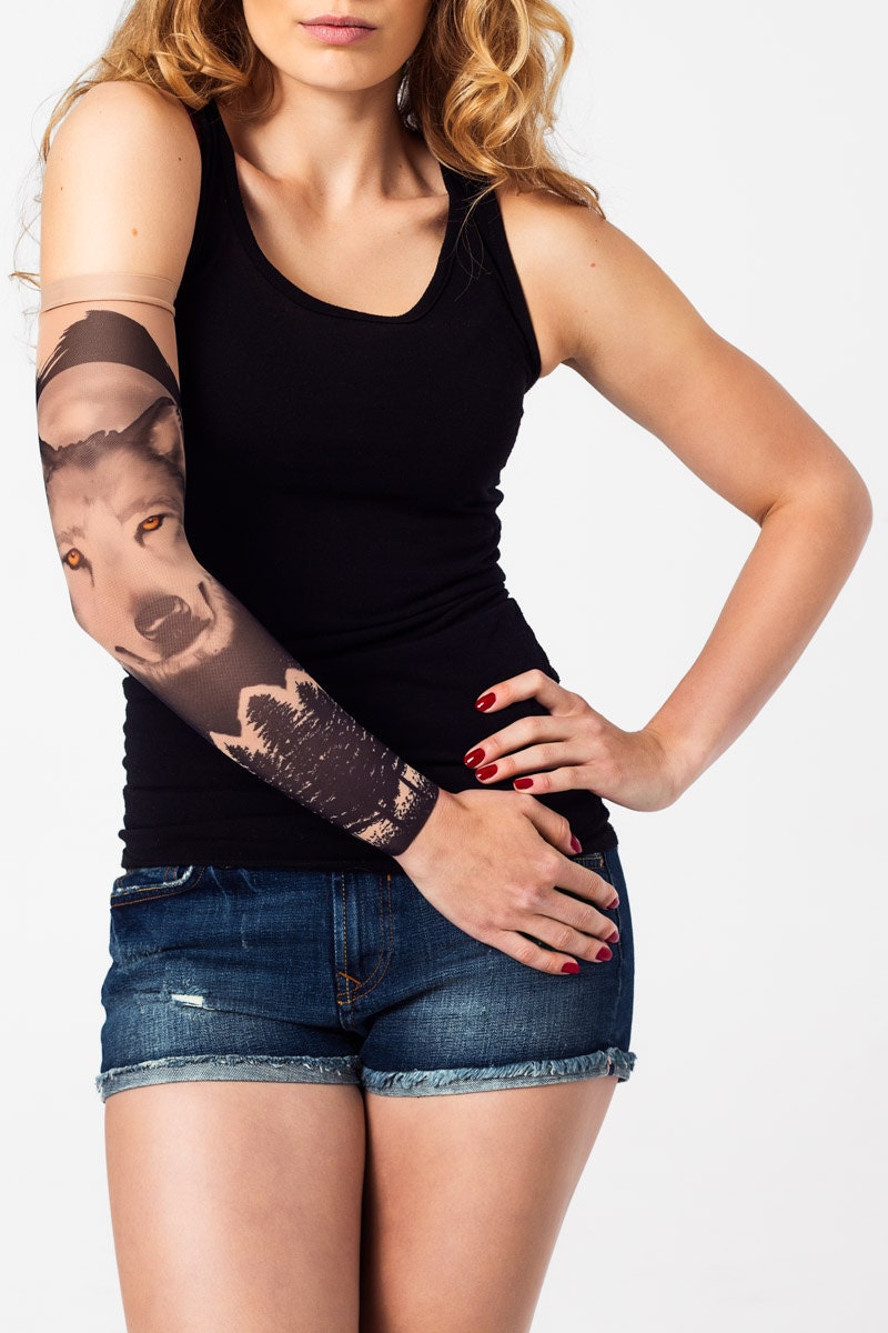 Rękaw z tatuażem wilka z żółtymi oczami i księżycem na damskiej ręce – widok z przodu