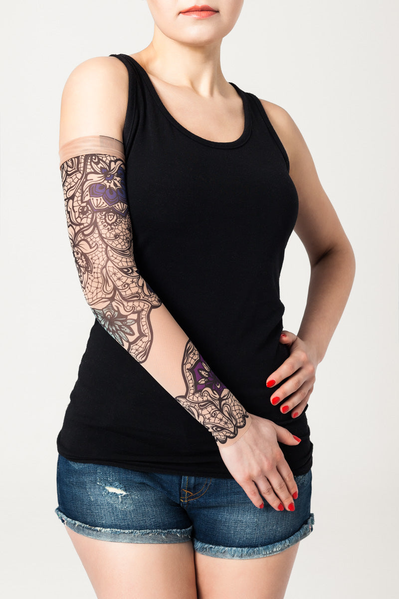 Rękaw z tatuażem niebiesko-fioletowych kwiatów i czarnej koronki w orientalnym stylu – na damskiej ręce, widok z przodu