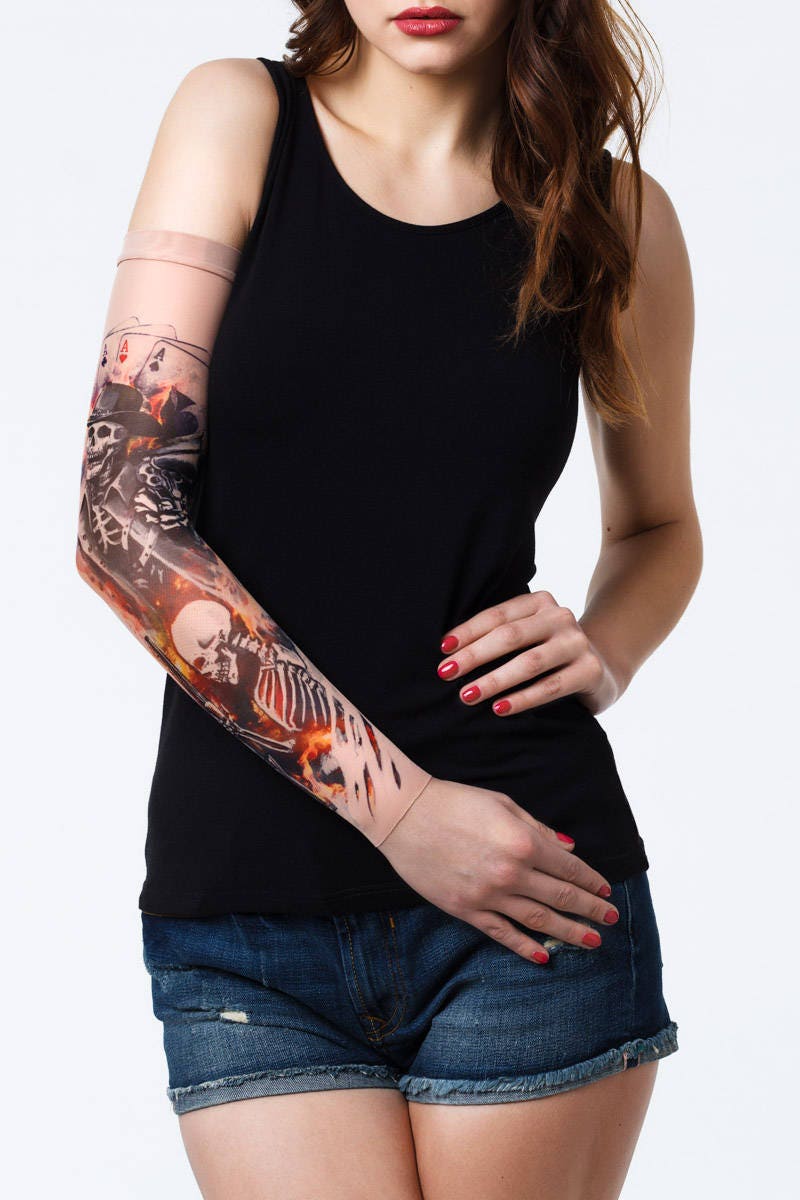 Rękaw z tatuażem szkieletowego kowboja z pistoletem i kartami do gry – na damskiej ręce, widok z przodu